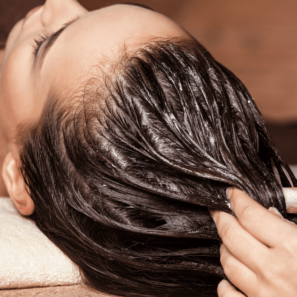 Person receiving a relaxing scalp massage with oil treatment at a spa.