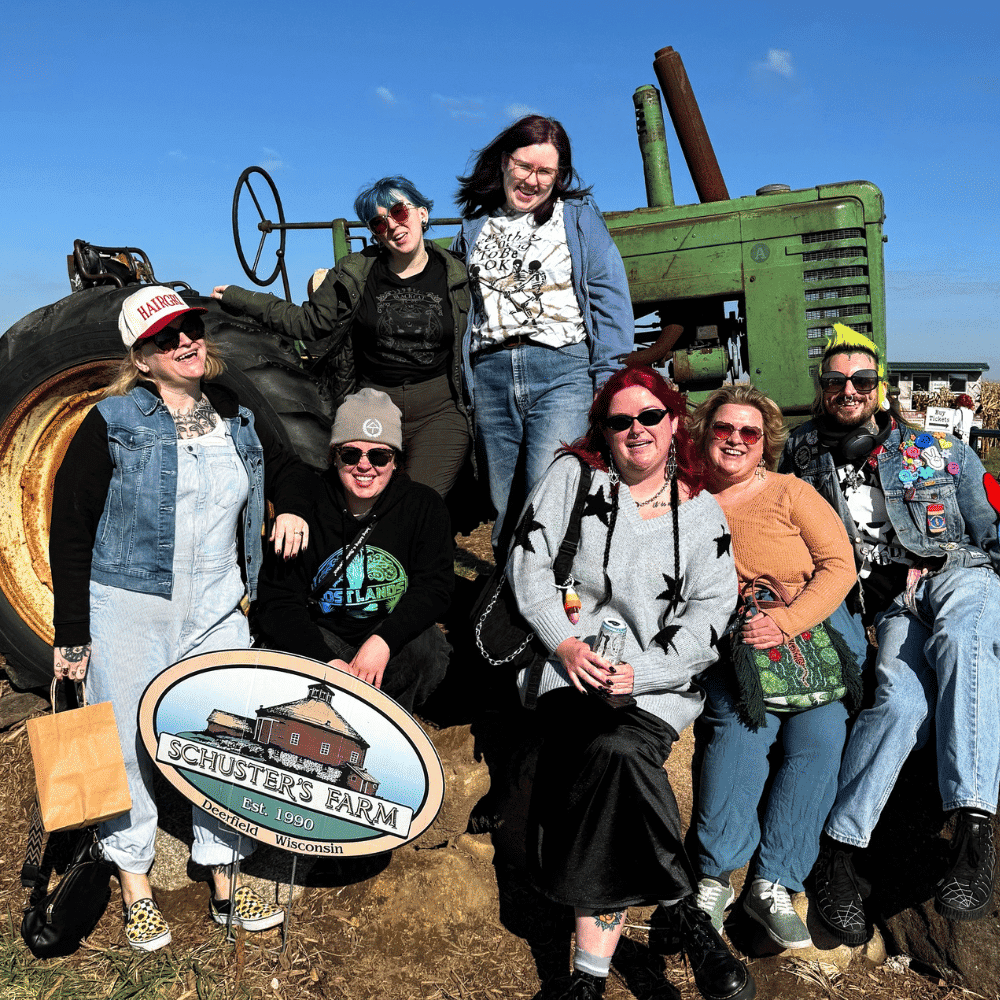 Group of people posing in front of a vintage green tractor at Schuster’s Farm.