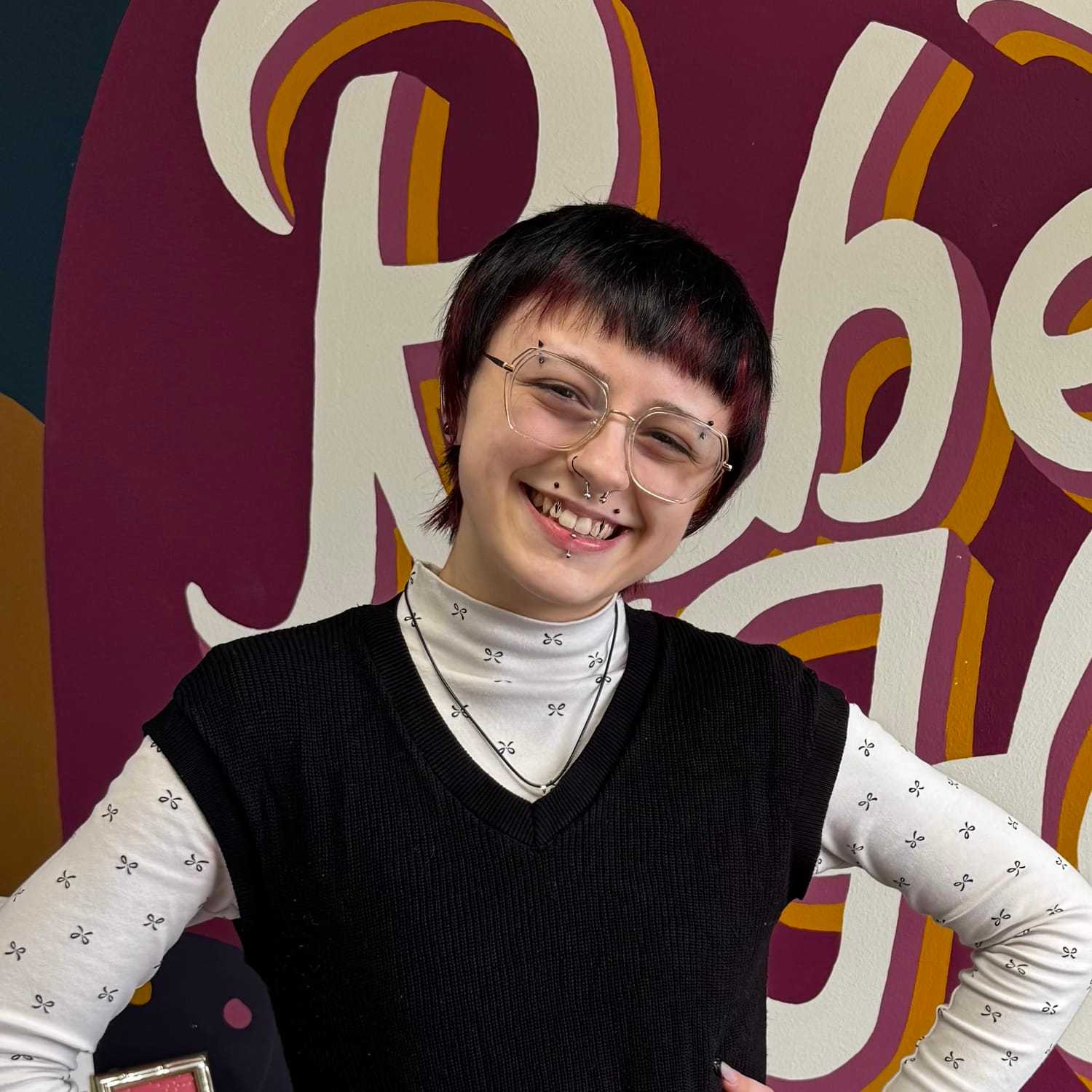 Portrait of TJ (She/They), a professional stylist at Rebel Hair, showcasing their expertise and style.